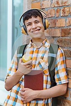Happy teen boy portrait on the way to school, he is eating an apple, education and back to school concept