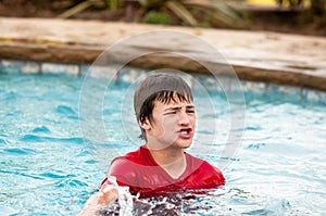 Happy teen boy in swimming pool with lips puckered.