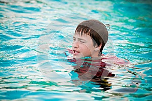 Happy teen boy in swimming pool with lips puckered.