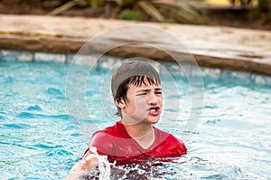 Happy teen boy in swimming pool with lips puckered. photo