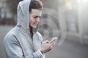 Happy teen boy walking on the street and using a smart phone