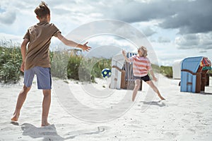 Happy teen children joyful playing voleyball on white summer beach at holidays