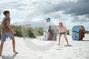 Happy teen children joyful playing voleyball on white summer beach at holidays