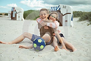 Happy teen children sitting and joyful talking on beach at sea at summer holidays