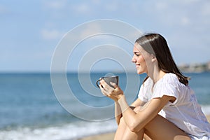 Happy teen drinking coffee contemplating on the beach