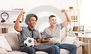 Happy teen football fans watching soccer on tv