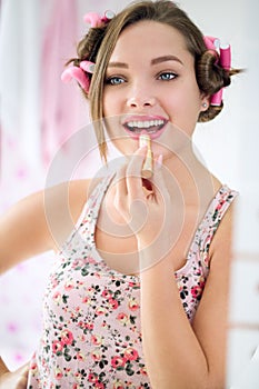 Happy teen girl applying lipstick