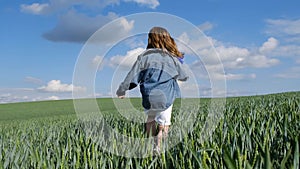 Happy teen girl in the countryside running across the field. Happy farmer girl on wheat field.