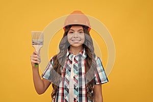 happy teen girl with curly hair in construction helmet hold painting brush, painting