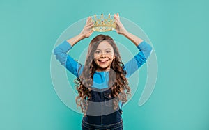 happy teen girl with curly hair wear crown on blue background, egoist