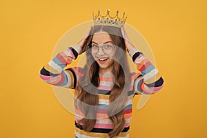 happy teen girl in glasses wear princess crown on yellow background, prom