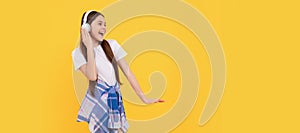 Happy teen girl in headphones singing along to song yellow background. Child portrait with headphones, horizontal poster