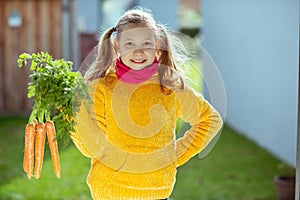 Happy teen girl with his fresh vegetables in yellow pullover excited about her harvest