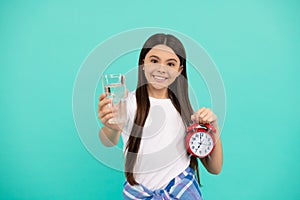 happy teen girl hold glass of water and alarm clock to keep daily water balance in time, drink water