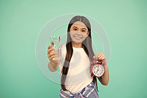 happy teen girl hold glass of water and alarm clock to keep daily water balance in time, drink water