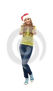 A happy teen girl holding thumbs up in a Christmas hat