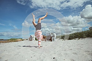 Happy teen girl joyful jumping on white beach at Baltic sea at summer holidays