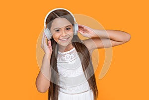 happy teen girl listening music in headphones on yellow background