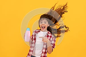 happy teen girl with long curly hair hold shampoo bottle, keratin