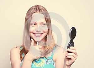 Happy teen girl looking at the mirror