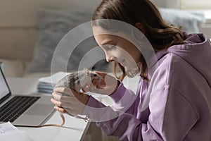 Happy teen girl playing with domesticated rat pet at home