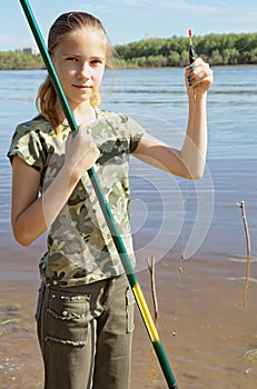 Happy teen girl preparing to fishing on the river