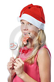 Happy teen girl in red cap eating Christmas cookie isolated