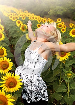 Happy teen girl rejoices in field of sunflowers