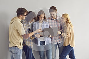 Happy teen girl showing laptop to smiling teenager friends studio portrait