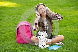 Happy teen girl singing song on grass after school, music. back to school. pupil at school time.