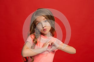 The happy teen girl standing and smiling against red background.