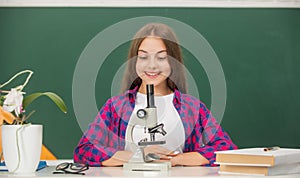 happy teen girl using microscope. back to school. study biology, chemistry laboratory