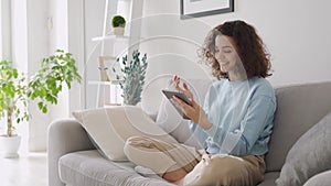 Happy teen girl using tablet enjoying online virtual chat video call at home.