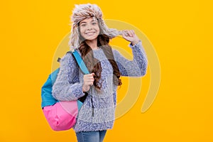 happy teen girl wear earflap hat with school bag on yellow background with copy space, school