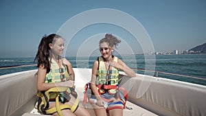 Happy teen girl on a yacht sitting with safety belts