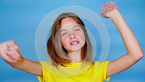 Happy teen girl in a yellow t-shirt is dancing, smiling and fools around