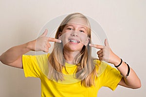 Happy teen girl in yellow t-shirt showing her dental brace.