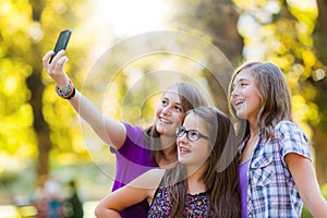Happy teen girls taking selfie in park