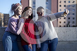 Happy teen girls taking selfie in park with mobile phone outdoors