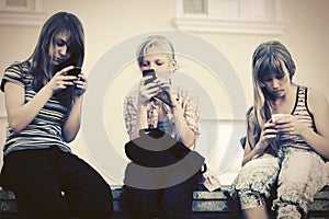 Happy teen girls using smart phones against a school building