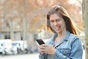 Happy teen holding a cell phone looking at you