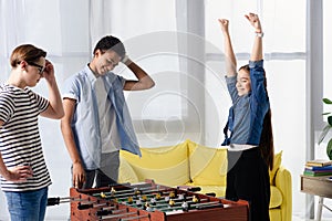 happy teen kid winning table football at multicultural teenagers