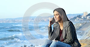 Happy teen talking on phone on the beach