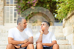 Happy teen young boy rest on stairs speak with elderly father enjoy leisure family weekend.