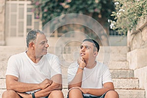 Happy teen young boy rest on stairs speak with elderly father enjoy leisure family weekend.