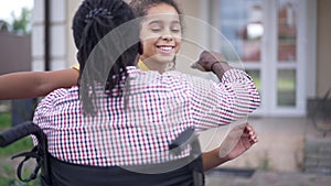 happy teenage African American girl hugging disabled man in wheelchair smiling looking at camera. Portrait of cheerful