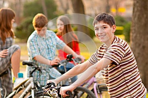 Happy teenage boy on bicycle with friends