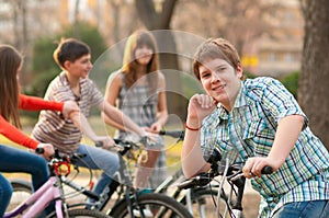 Happy teenage boy on bicycle with friends