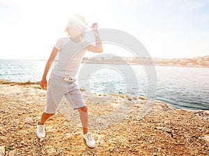 Happy teenage boy dancing on the beach in summer
