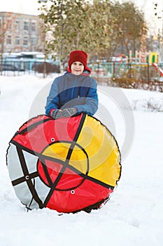 Happy teenage boy sliding down hill on snow tube Snow tubing on winter day outdoors. Winter activity, active leisure and entertain